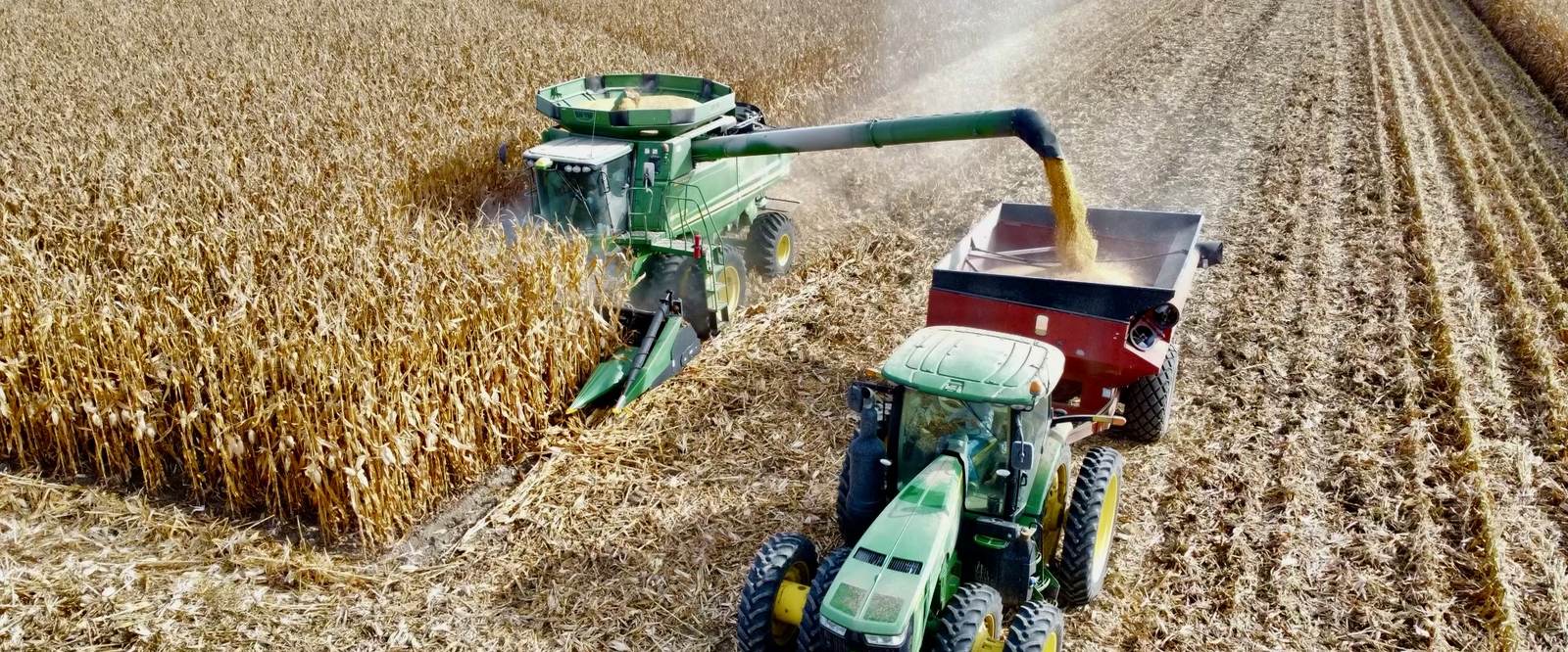 Aerial view of a combine unloading corn into a grain cart during harvest